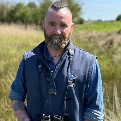 Paul Hadaway, Director of Conservation & Engagement at KWT, in a field with binoculars.